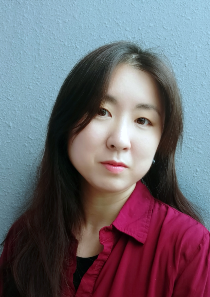 An image of board member Eugenia Kim with dark hair, wearing a red shirt and on a blue background